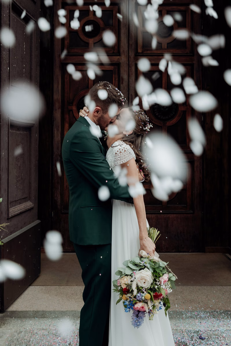 sposi si baciano fuori dalla chiesa durante il lancio del riso - fotografo matrimonio milano